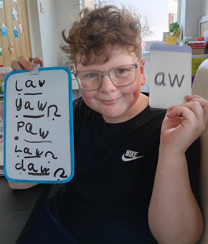 A pupil showing off their spelling practice with a smile